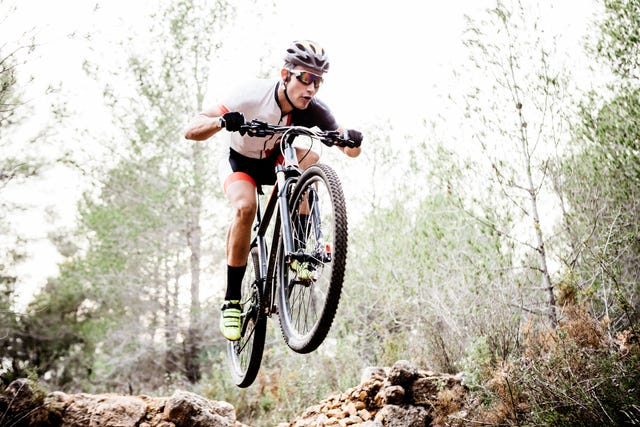 un ciclista pasa volando sobre las piedras del terreno durante una ruta en bicicleta de montaña