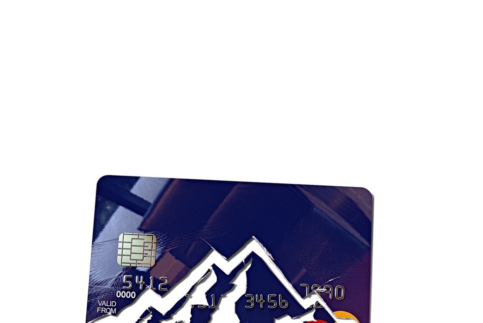 a blue credit card cut up to look like mountains, on a light wooden desk 