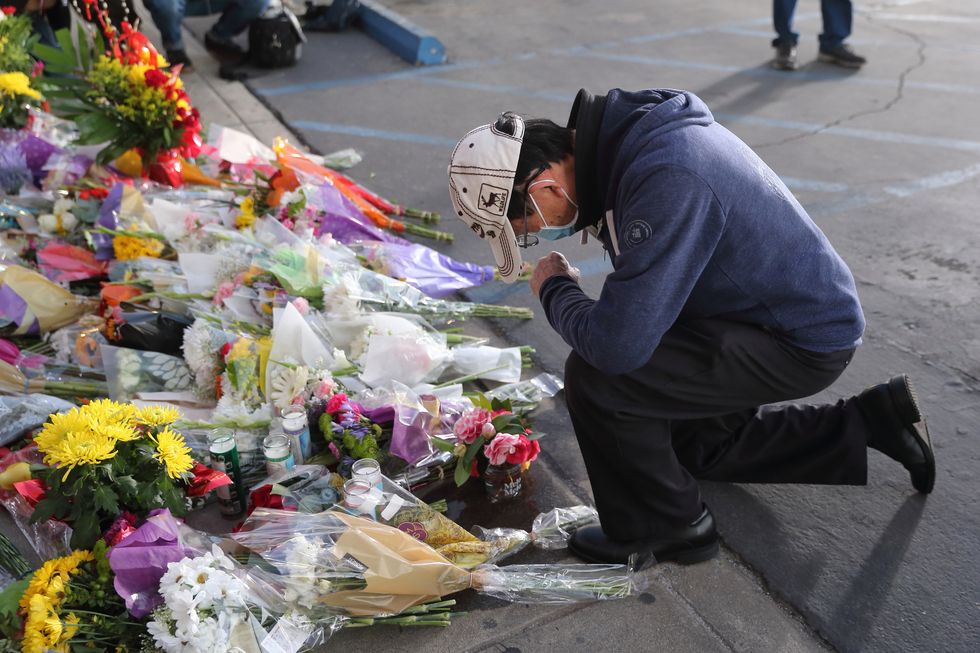 a man kneels before a makeshift vigil