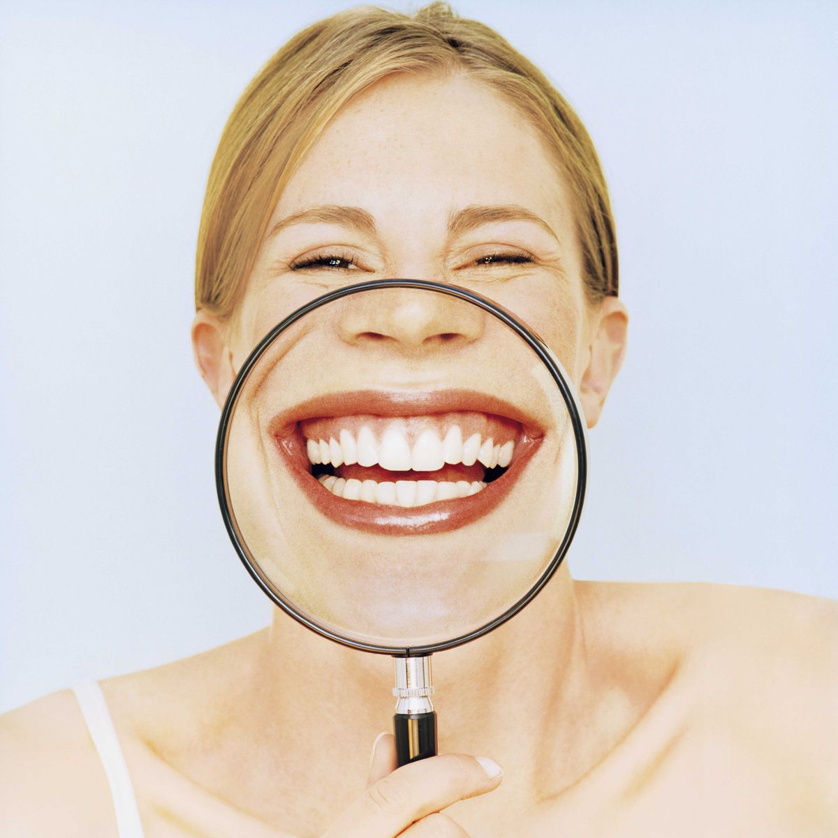 woman holding magnifying glass in front of mouth, smiling, portrait id 200267250 001