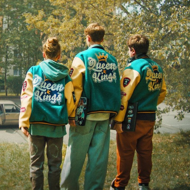 three kids in matchiing esports team jackets stand with their backs facing the camera in a scene from too old for fairy tales 2, a good housekeeping pick for best movies for kid 2024