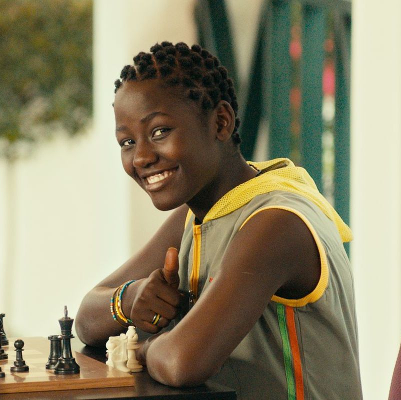 a young girl sits at a chessboard in a scene from queen of katwe, a good housekeeping pick for best tween movies