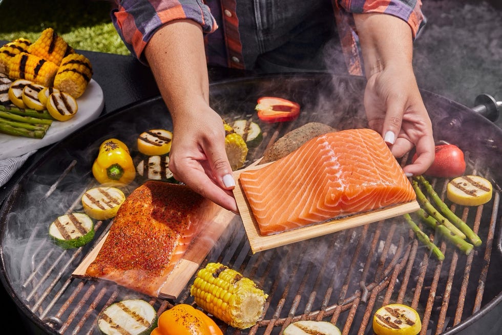 person grilling salmon and assorted vegetables