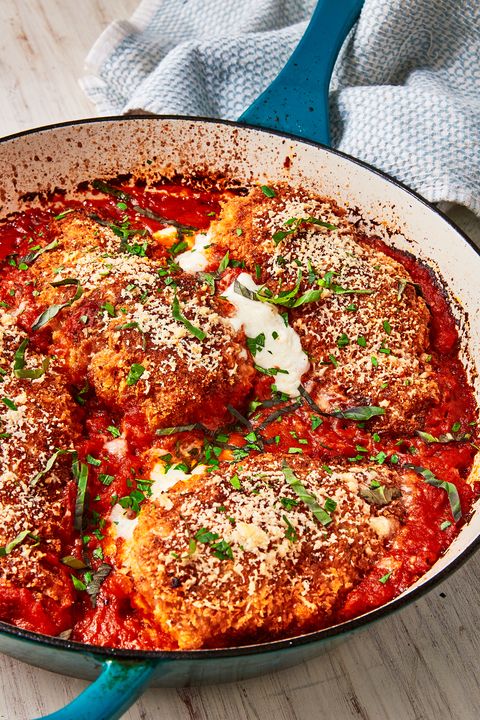 mozzarella stuffed chicken parm breasts topped with cheese, chiffonade basil, and breadcrumbs, in a blue skillet