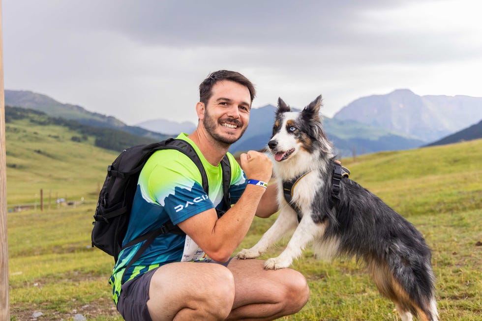 a person with a backpack interacting with a dog in a scenic outdoor setting