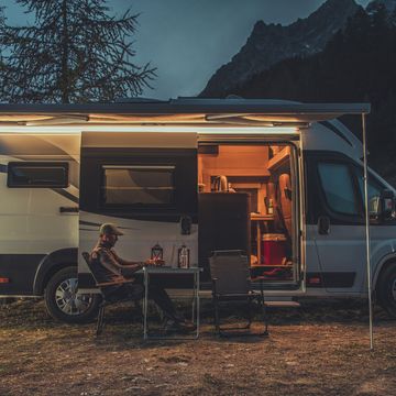 caucasian men in his 40s working online while on vacation in mountain region remote work on laptop while camping in a wild camper van as mobile office theme