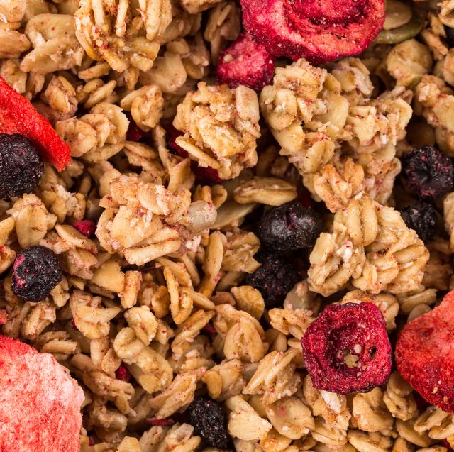 muesli cereals close up background with raisins, oat and wheat flakes, fruits, strawberry, cranberry, cherry pieces