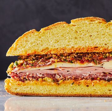 a layered muffuletta sandwich with meat, cheese, and olive salad