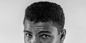 black and white photo of muhammad ali, facing the camera with boxing gloves on