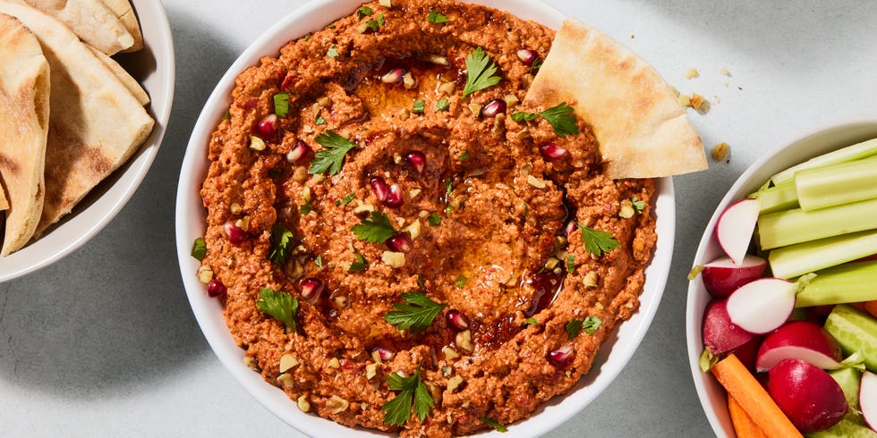 muhammara dip garnished with herbs and pomegranates with crudites