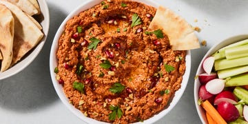muhammara dip garnished with herbs and pomegranates with crudites