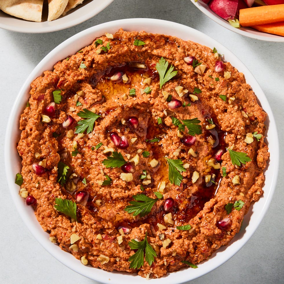 muhammara dip garnished with herbs and pomegranates with crudites