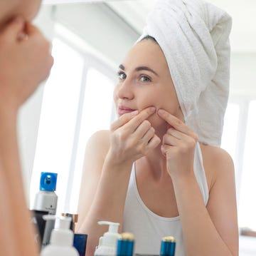 Un mujer con acne se mira en el espejo un mujer con una toalla en la cabeza con acne se mira en el espejo
