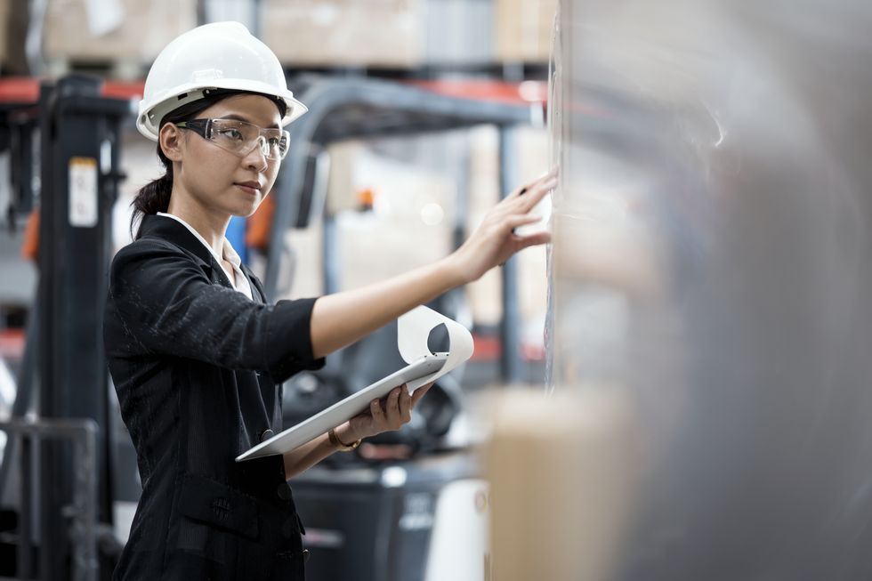 una mujer con casco y gafas supervisa una máquina en una fábrica