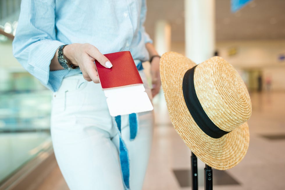 Mujer con un billete de viaje en la mano y un sombrero en la maleta