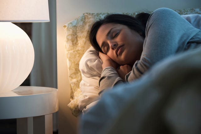 mujer durmiendo de noche con lámpara encendida