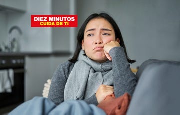 una mujer vestida de gris enferma y abrigada en un sofa