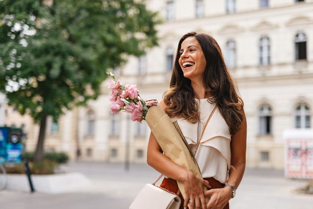 una mujer morena sonrie paseando por la calle