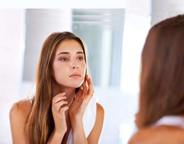 mujer tocandose la cara frente al espejo