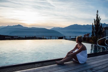 mujer relajándose en la piscina de un spa con vistas a la montaña