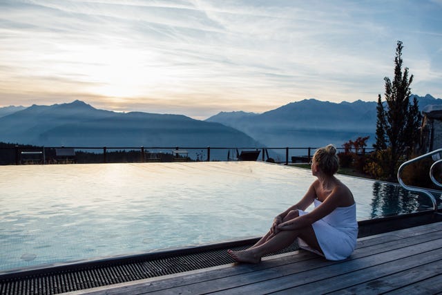 mujer relajándose en la piscina de un spa con vistas a la montaña