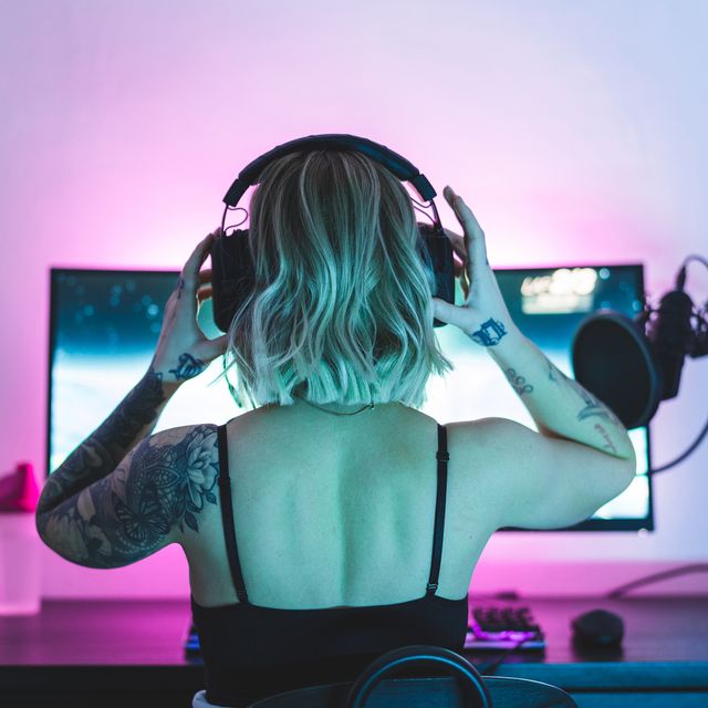 una 'gamer' y 'streamer' se coloca unos auriculares sentada a una mesa con un ordenador enfrente