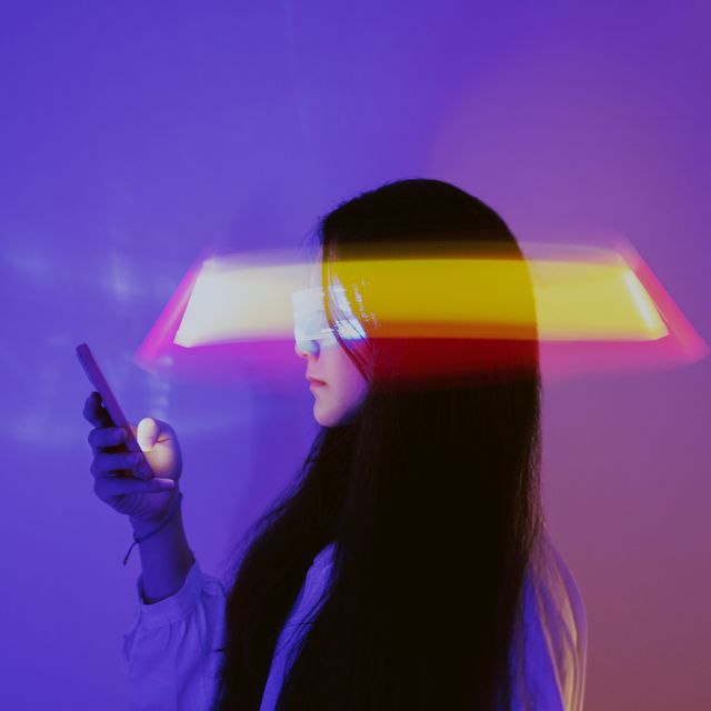 una mujer asiática utiliza su móvil rodeada de luces