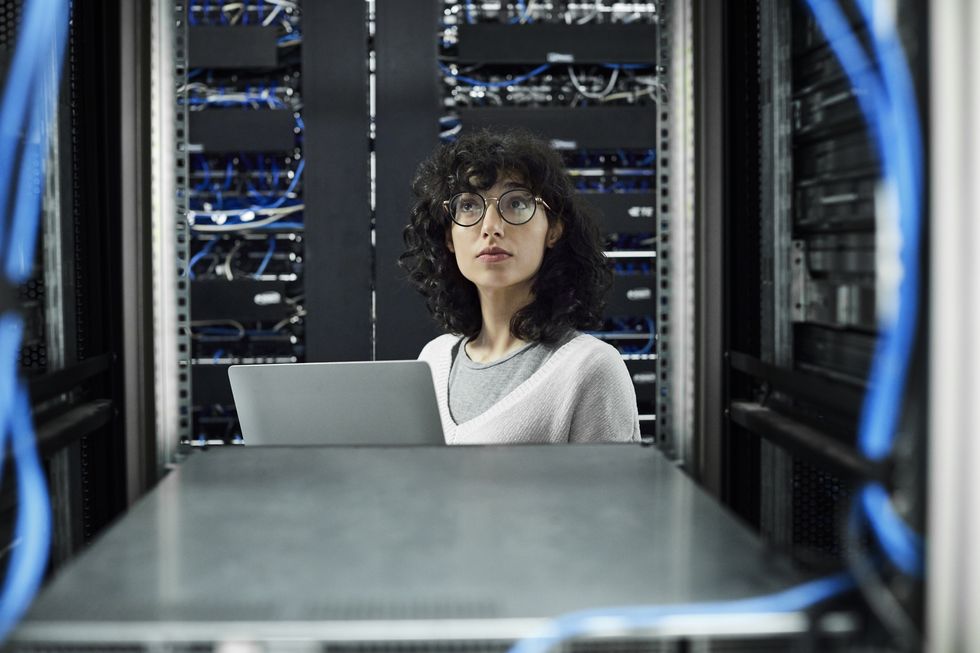 una mujer con gafas y el pelo rizado trabaja en un servidor informático