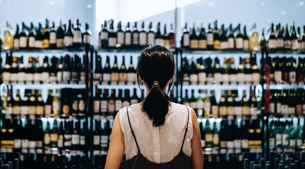 mujer ante el lineal de vinos del supermercado