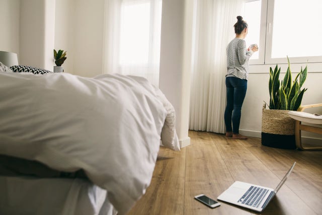 Mujer aislada en una habitación mira por la ventana