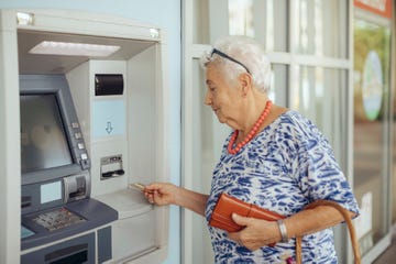 una señora jubilado, tarjeta en mano, se dispone a sacar dinero de un cajero automático