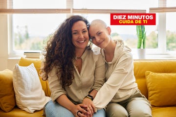dos mujeres con un gesto carinoso se cogen las manos sentadas en un sofa