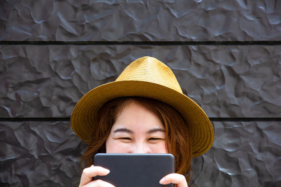 joven asiática jugando sonriente con su smartphone ellees