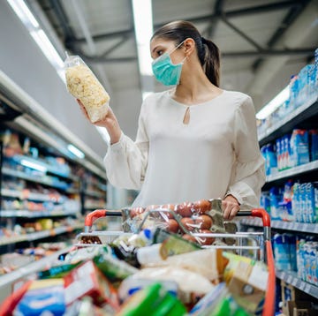Una mujer hace la compra en un supermercado con una mascarilla una mujer hace la compra en un supermercado con una mascarilla