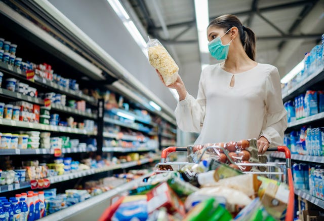una mujer hace la compra en un supermercado con una mascarilla