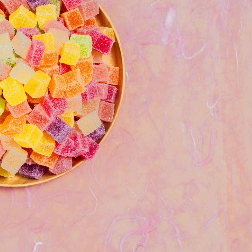 multi colored candies with candies and sweets rainbow in pink background