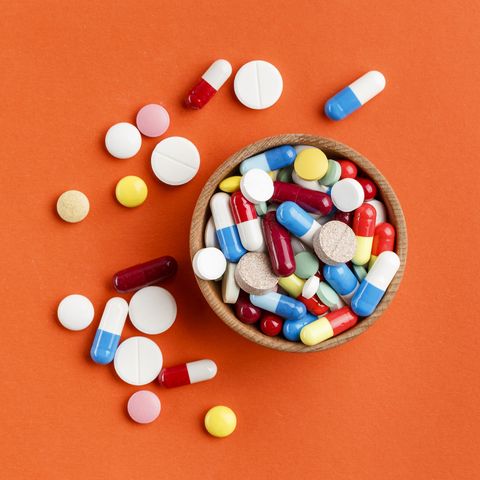 Multi-colored pills scattered on a bright background, a place for text.