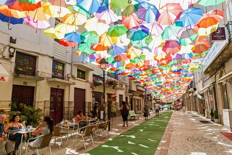 multi colored umbrellas hanging over a street in Águeda, portugal