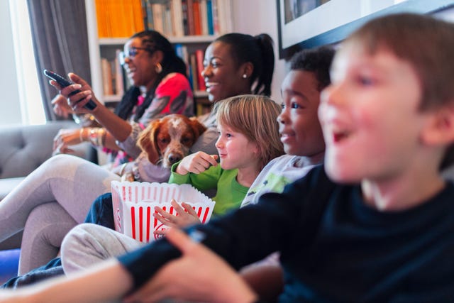 Multi-ethnic family watching movie and eating popcorn