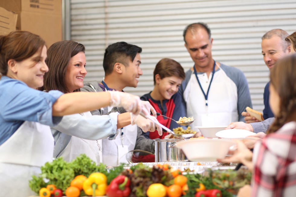 multi ethnic group of volunteers serves food at soup kitchen