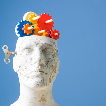 multicolored gears in mannequin head on blue bakcground