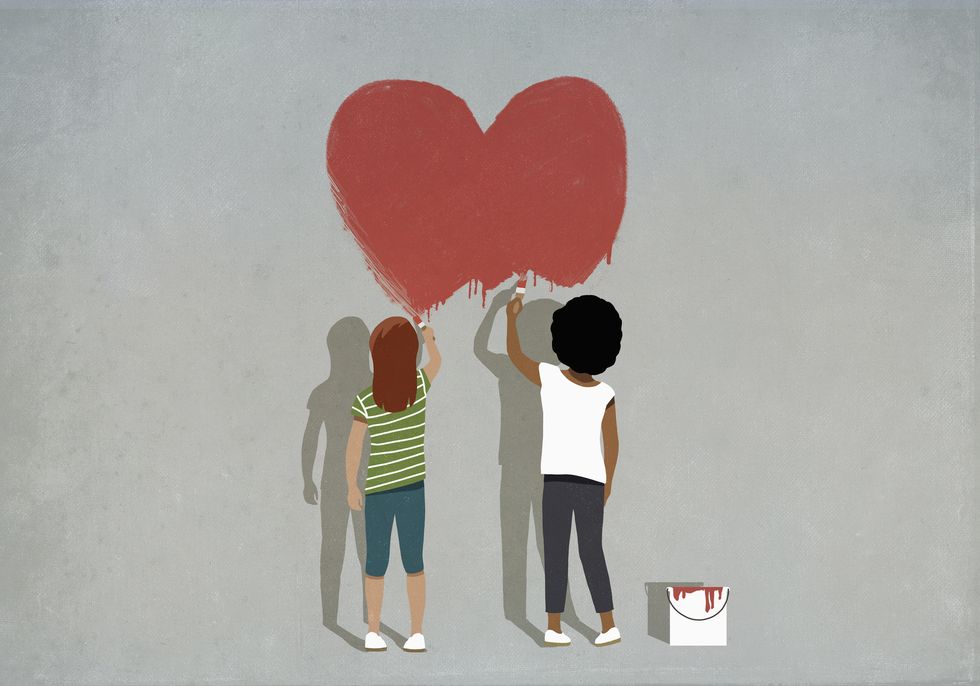 multiethnic girls painting red heart on wall