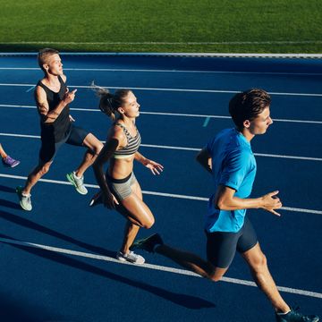 Multiracial athletes practicing Vita running on racetrack