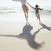 Mother and daughter holding hands and running on sunny beach multiracial family struggles