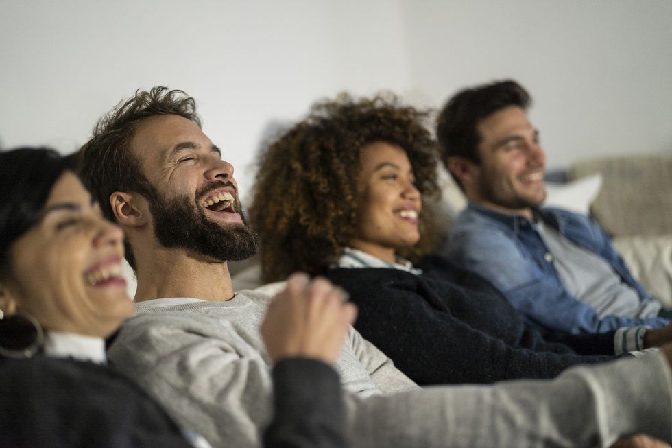 multiracial group of friends laughing out loud while watching movie