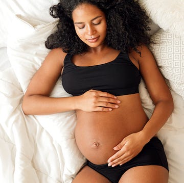 woman relaxing in underwear set on bump, cradling her bump which is on show