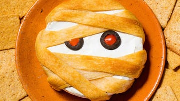 brie cheese wrapped in puff pastry with pepperoni and olive eyes