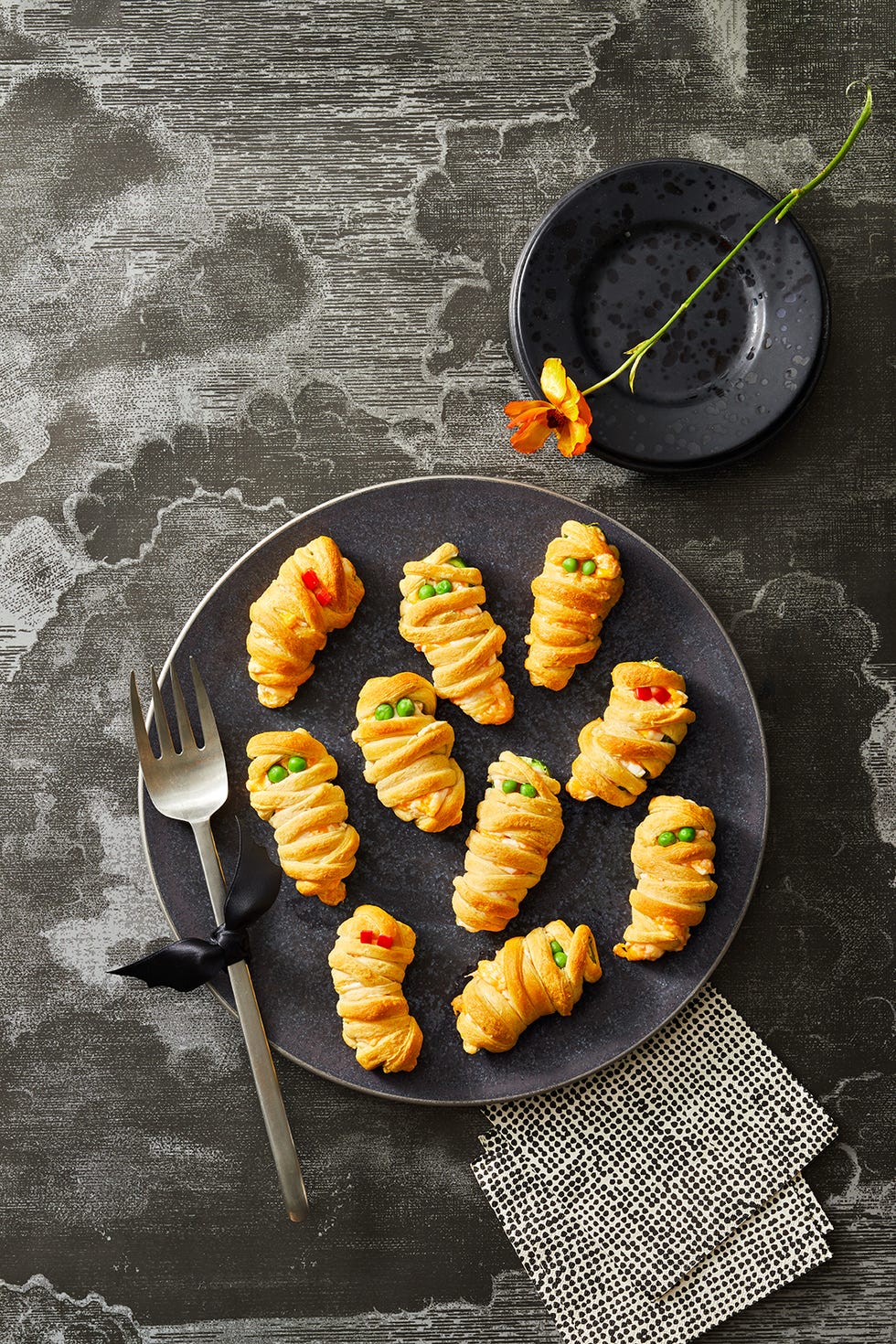 mummy jalapeno poppers on a black plate for halloween