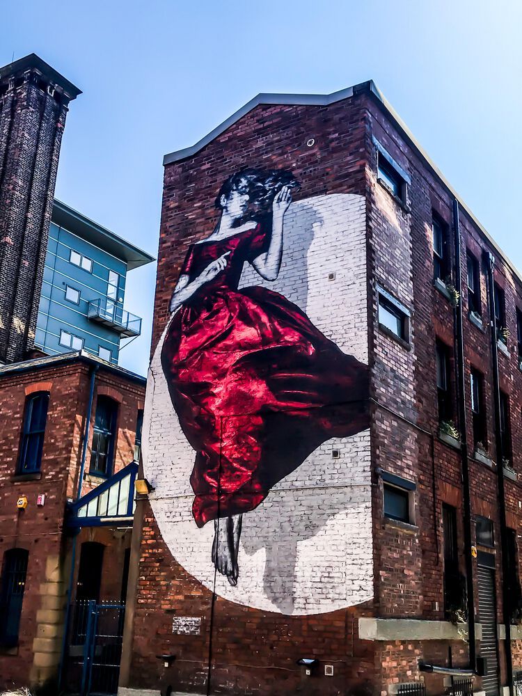 a mural in manchester featuring a woman in a red dress