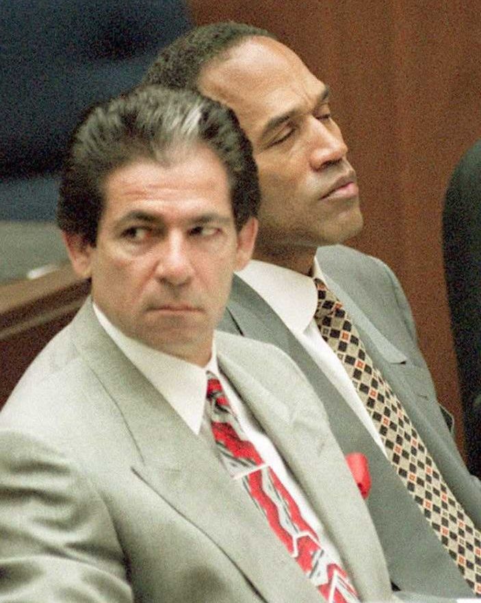 robert kardashian sitting and looking to his right as oj simpson leans forward with his eyes closed